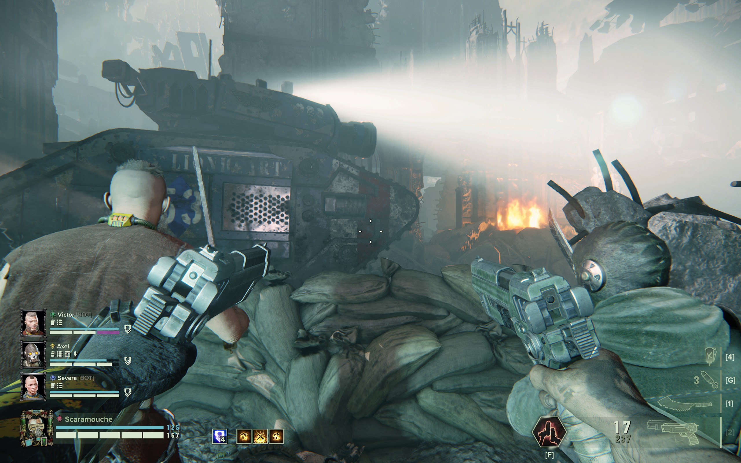 A tank with a shining headlight trundles past three players taking cover behind sandbags