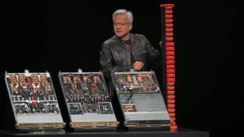 An image of the live presentation broadcast by Nvidia at Computex 2025, where CEO Jen-Hsun Huang holds an NVLink Fusion spine next to three Nvidia rank units.