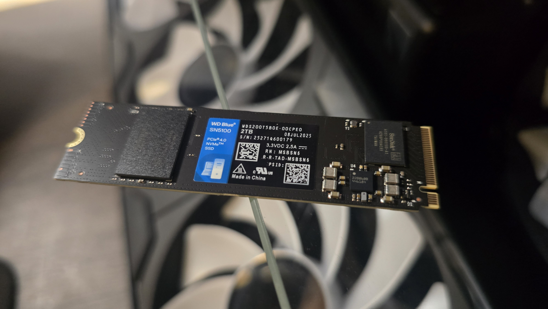 A WD Blue SN5100 ready to be installed inside a gaming PC.