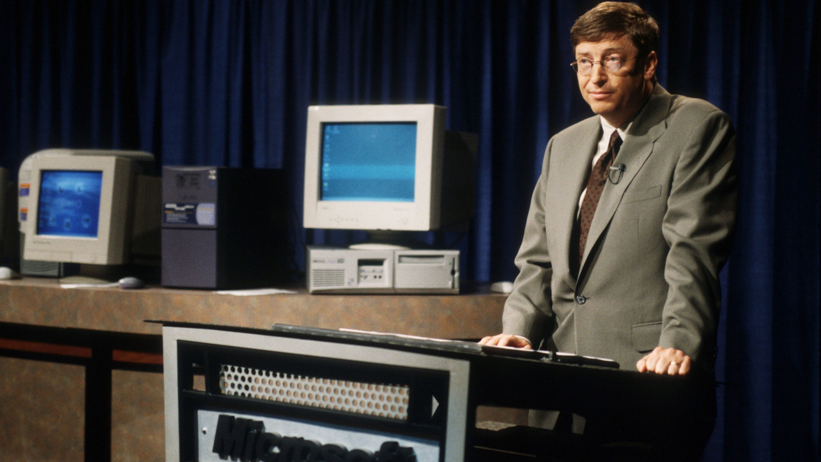 Bill Gates standing sheepishly at a presentation for Windows 98
