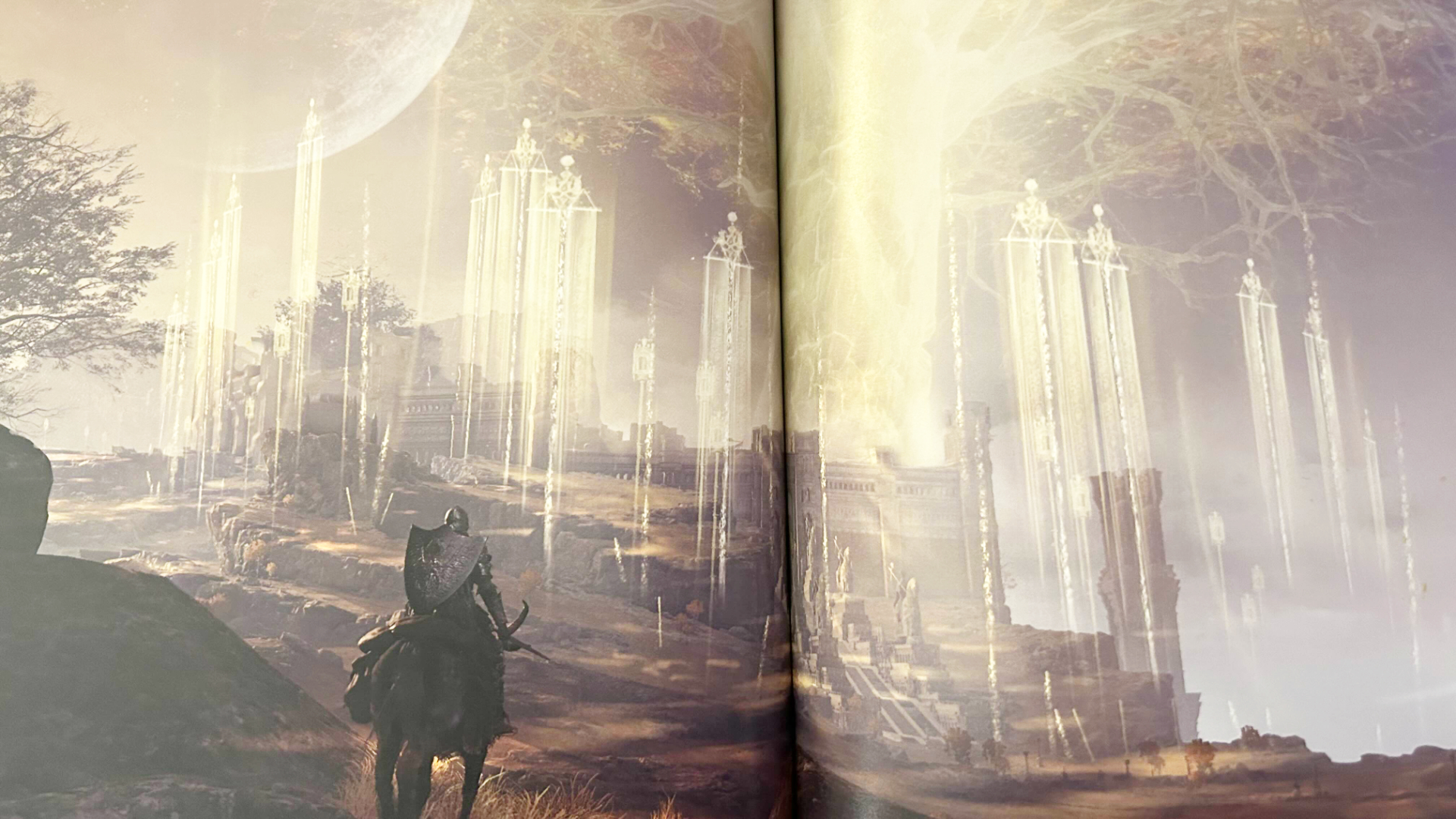 A photo of an Elden Ring concept art book. Two full pages of a hill covered in golden flags and the a bright tree in the distance.