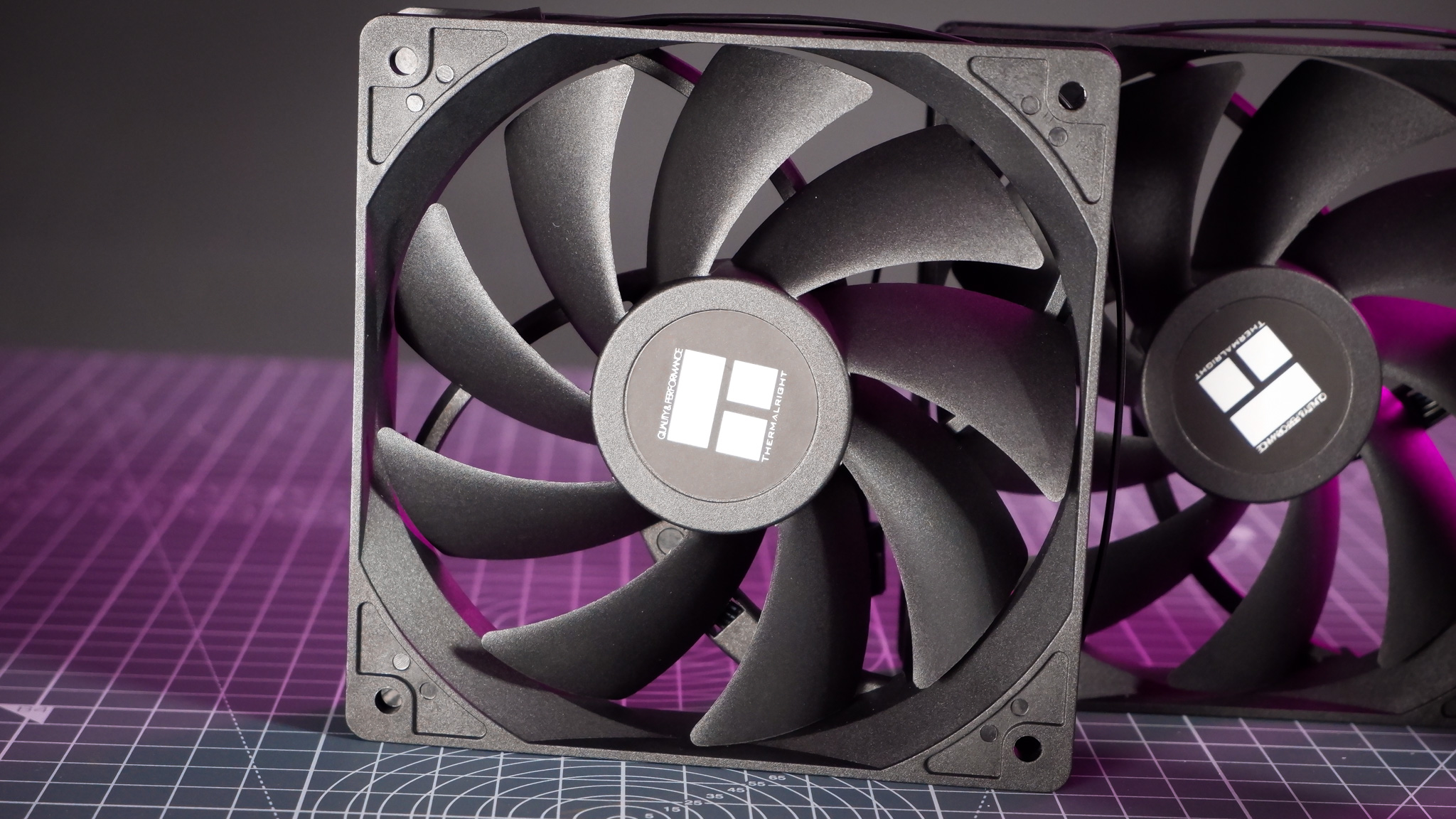 A Thermalright Peerless Assassin 120 SE cooler on a desk with the fans beside it.