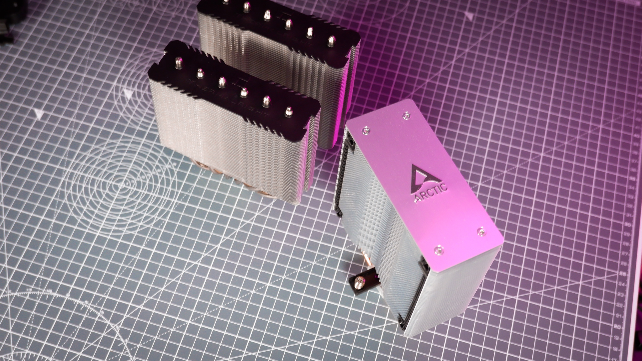 A Thermalright Peerless Assassin 120 SE cooler on a desk with the fans beside it.