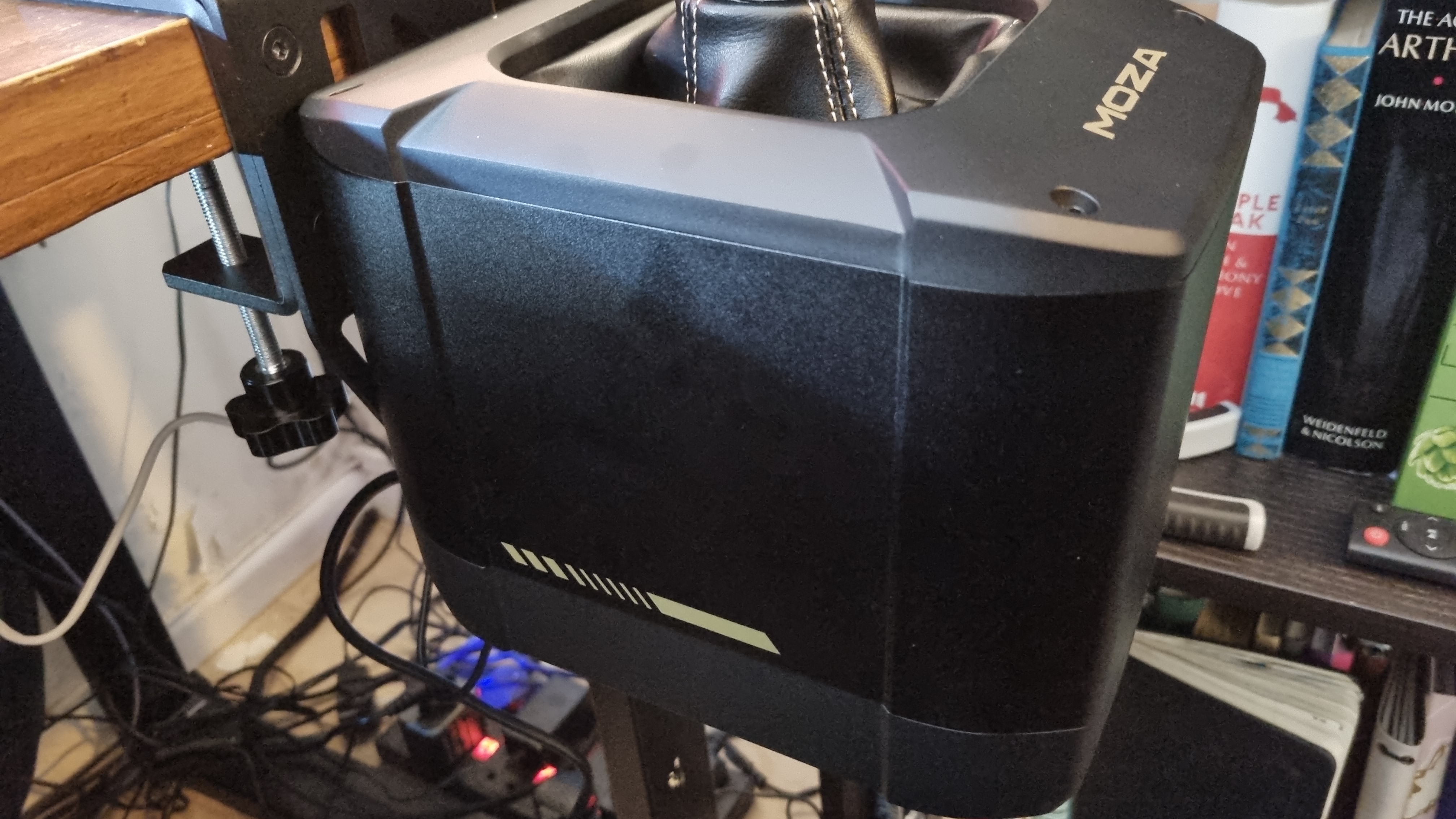 A close up of the Moza AB9 FFB Base attached to a desk