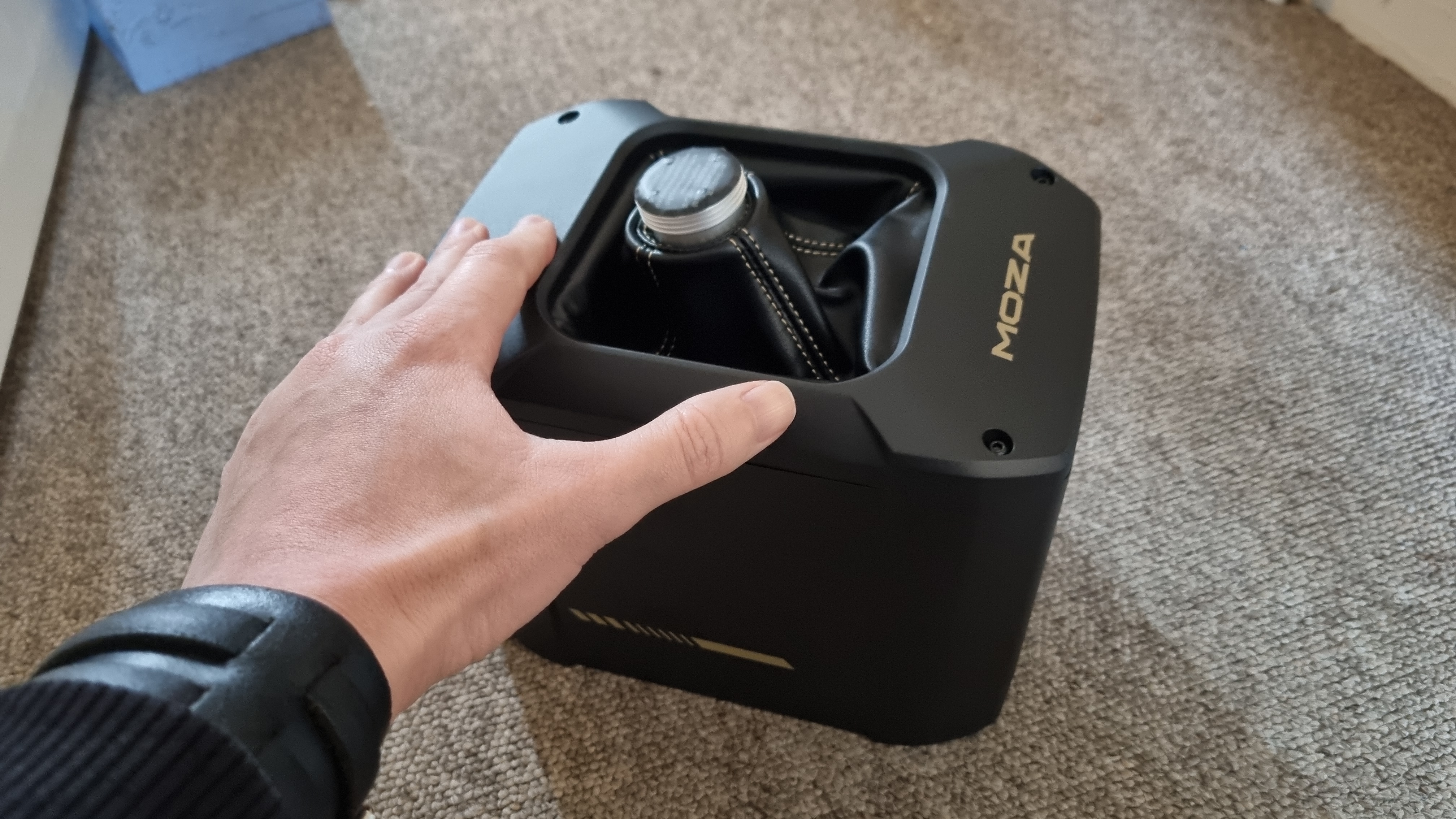 A Moza AB9 FFB base, with an outstretched hand in shot for scale