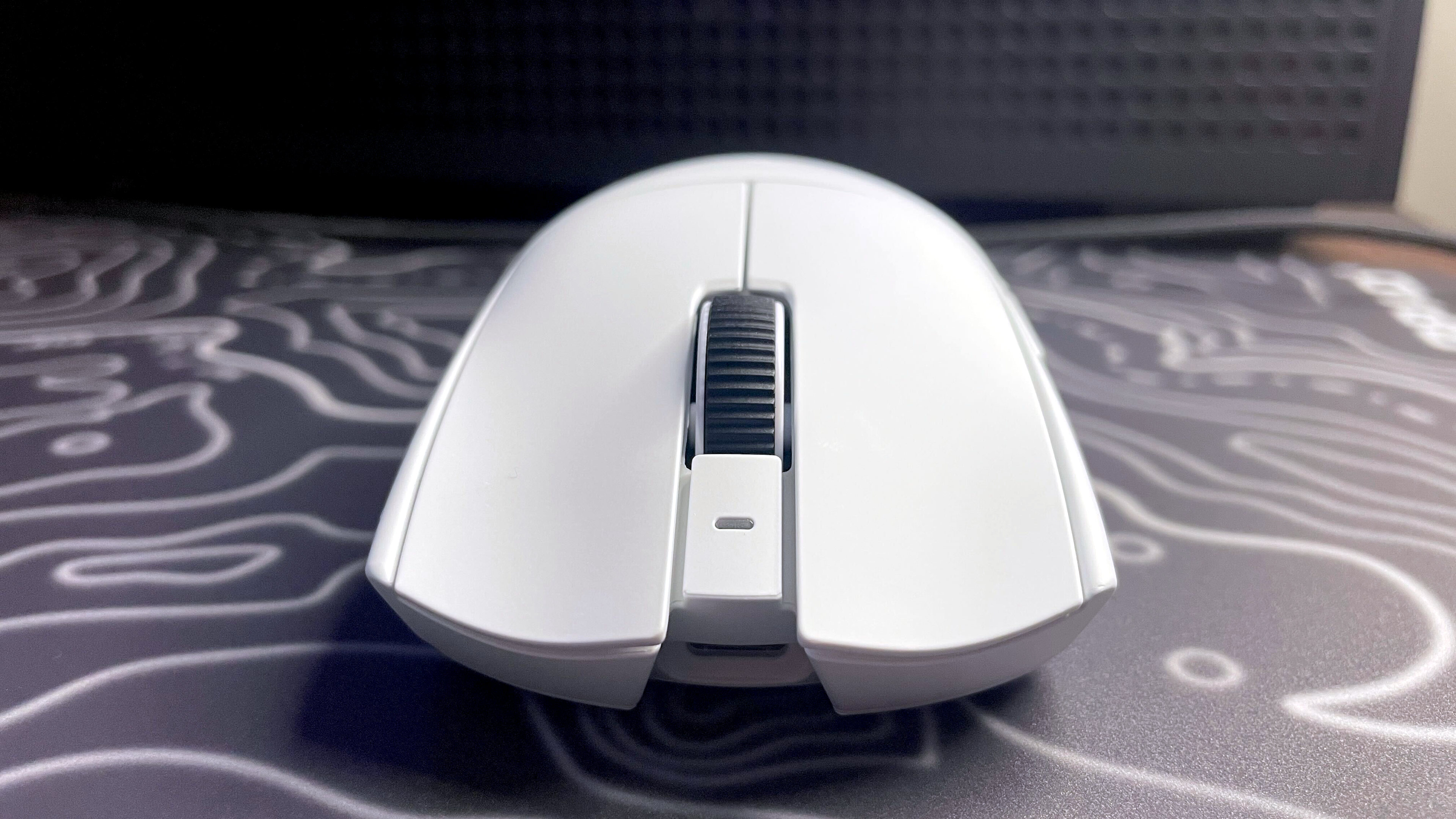 A photo of a white Razer Viper V4 Pro wireless gaming mouse on a colorful mouse pad