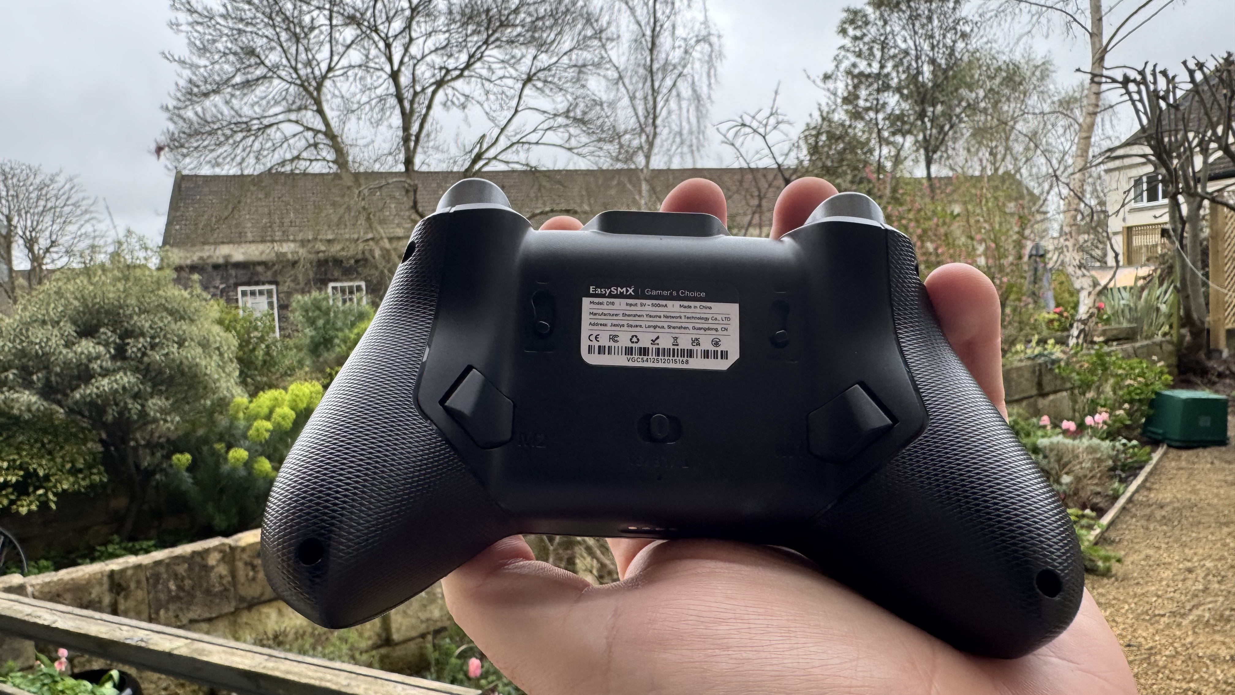 the back of the EasySMX D10 in a hand, in a garden