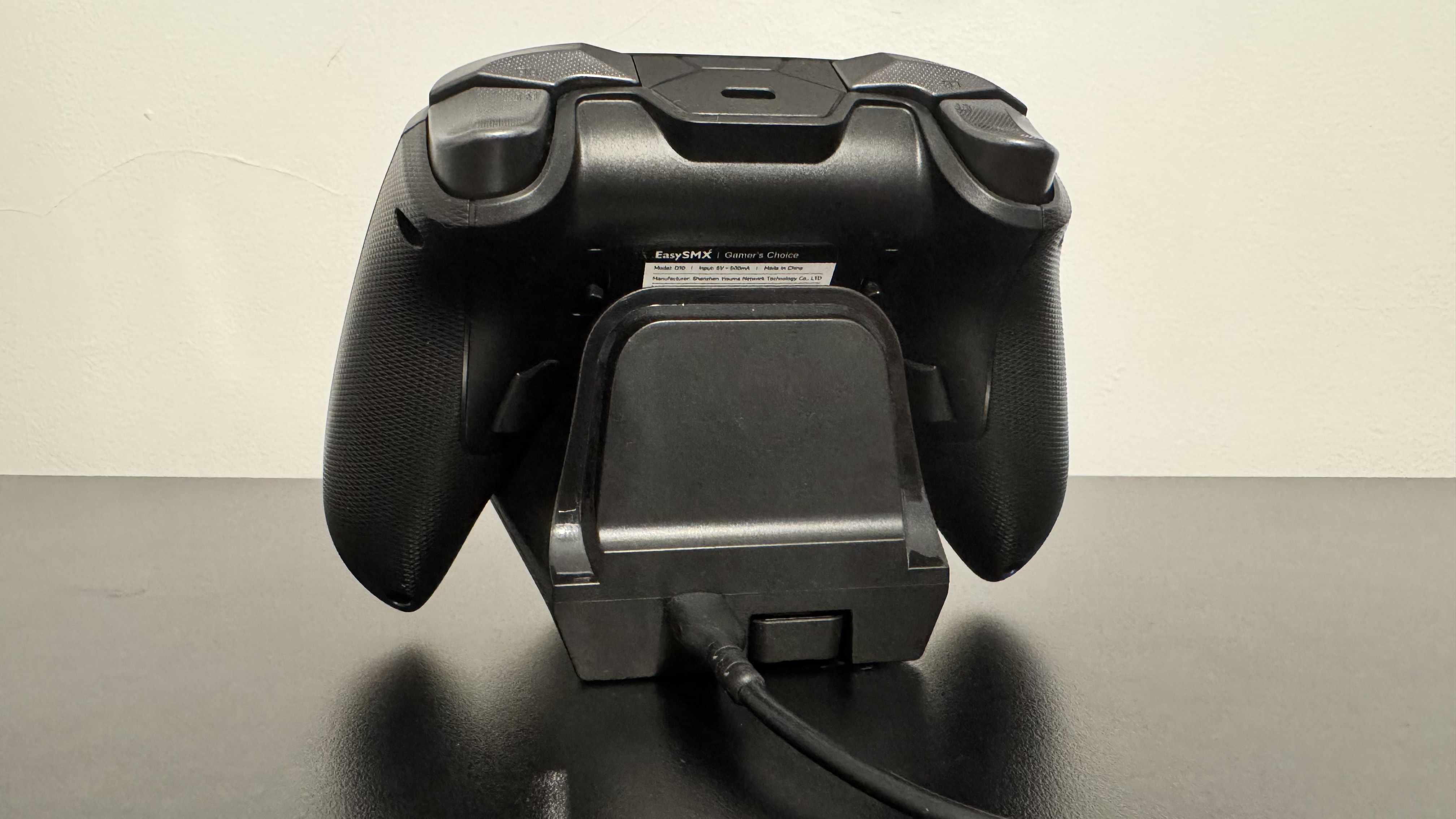 EasySMX D10 on a charging stand from the back, on a black desk