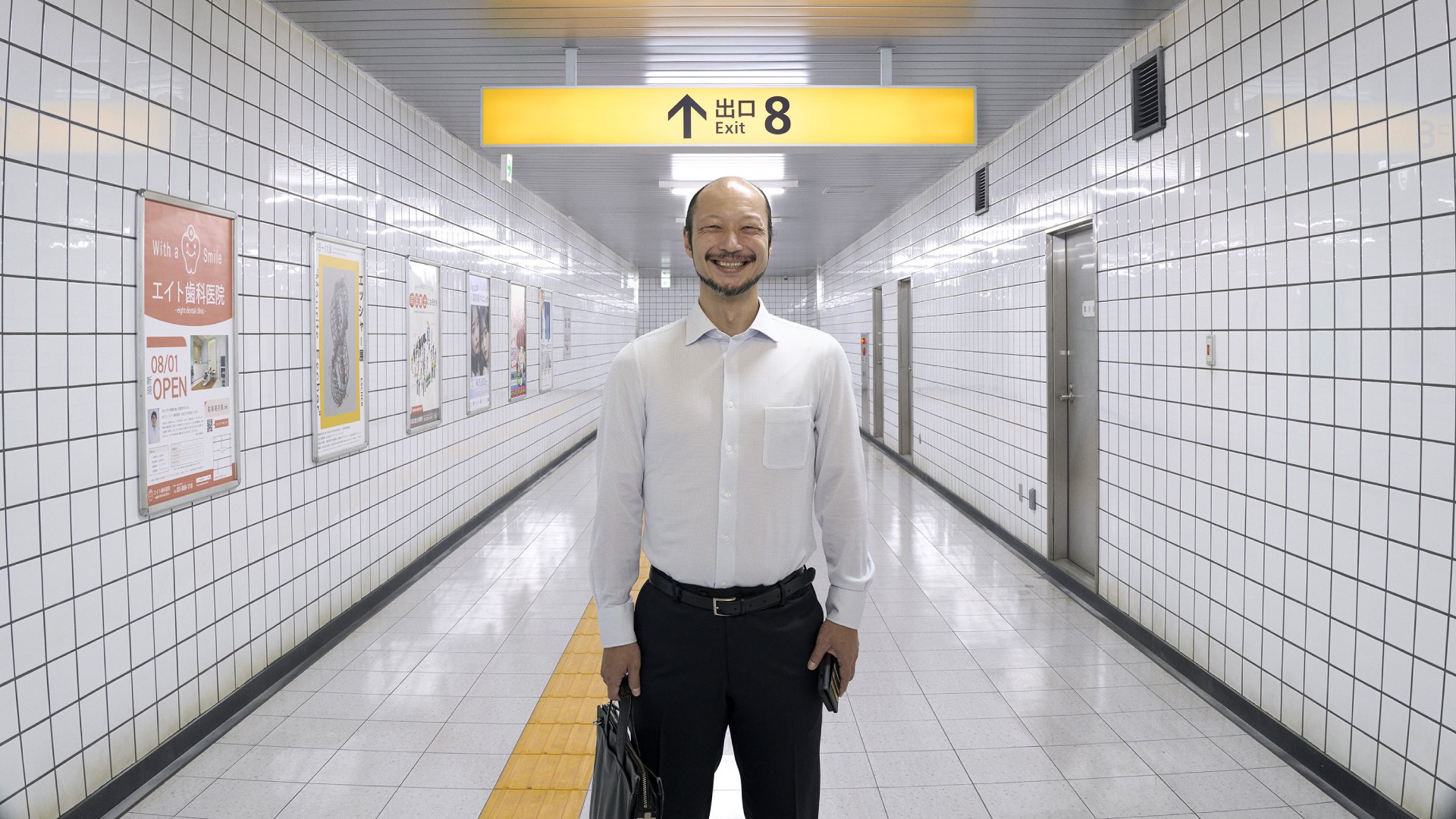 A man standing underneath the Exit 8 sign
