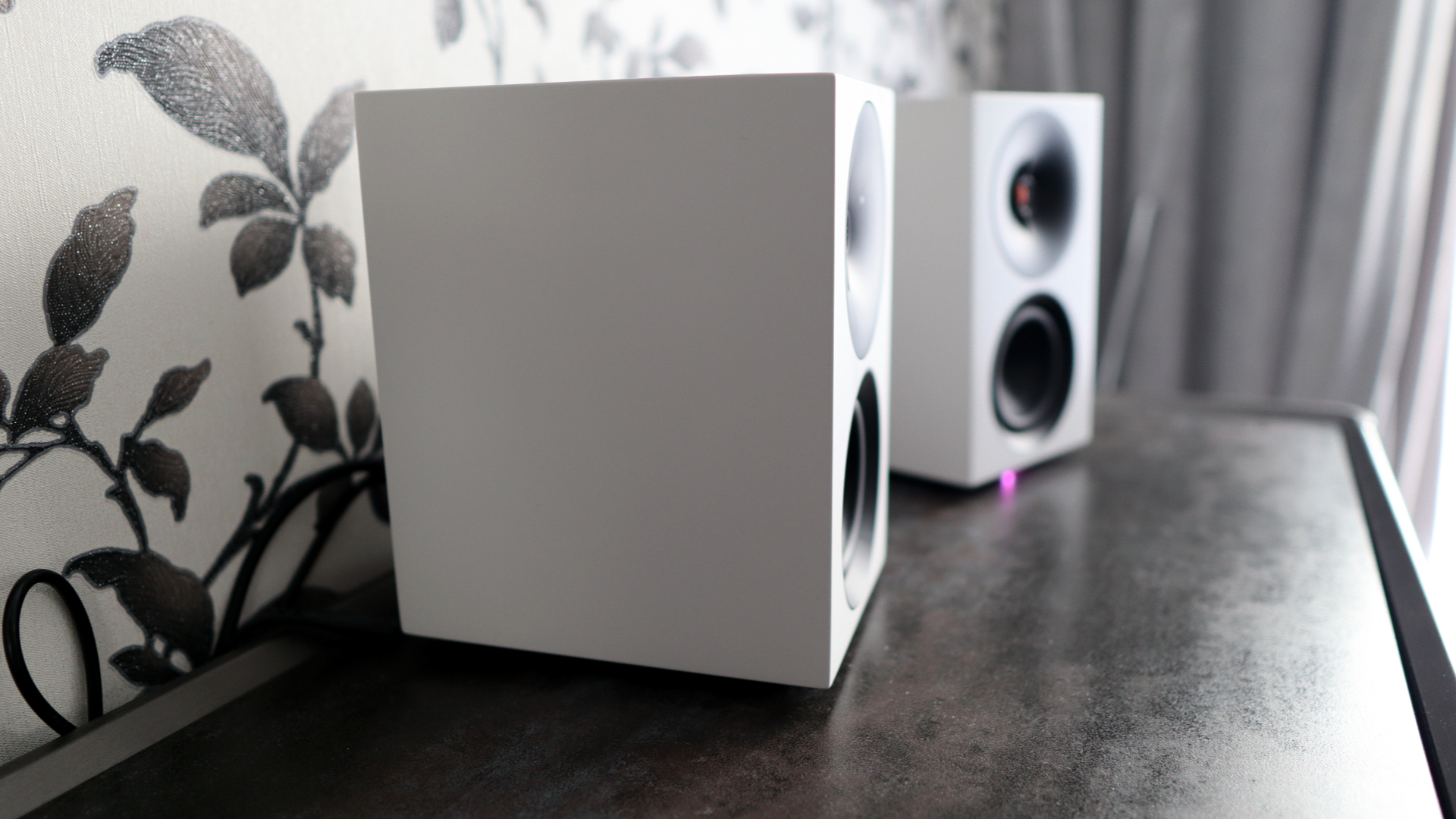 Cambridge Audio's L/R S speakers on a desk. The speakers are white with black tweeters.