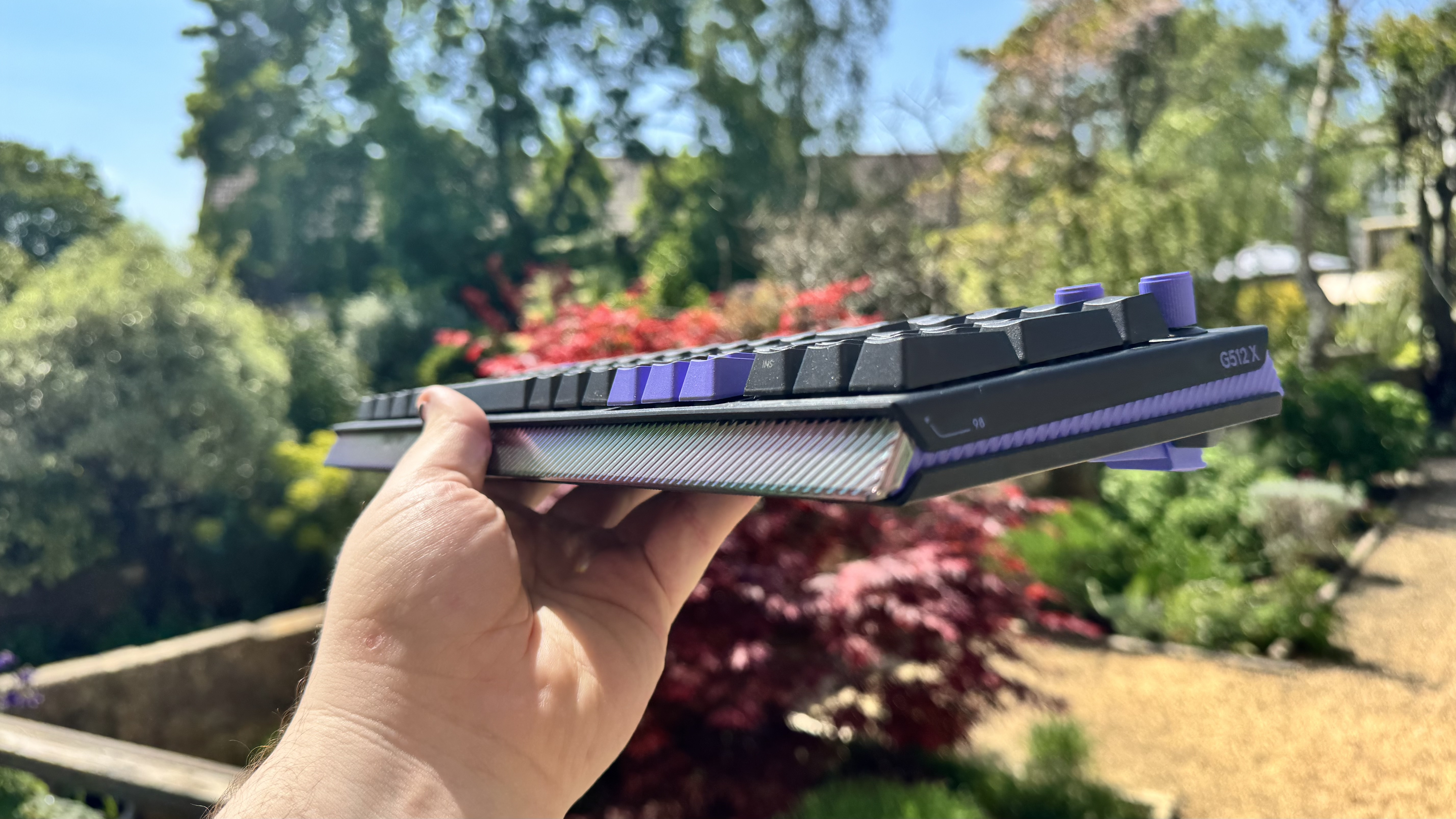 The Logitech G512 X gaming keyboard from the bottom, in a hand, outside