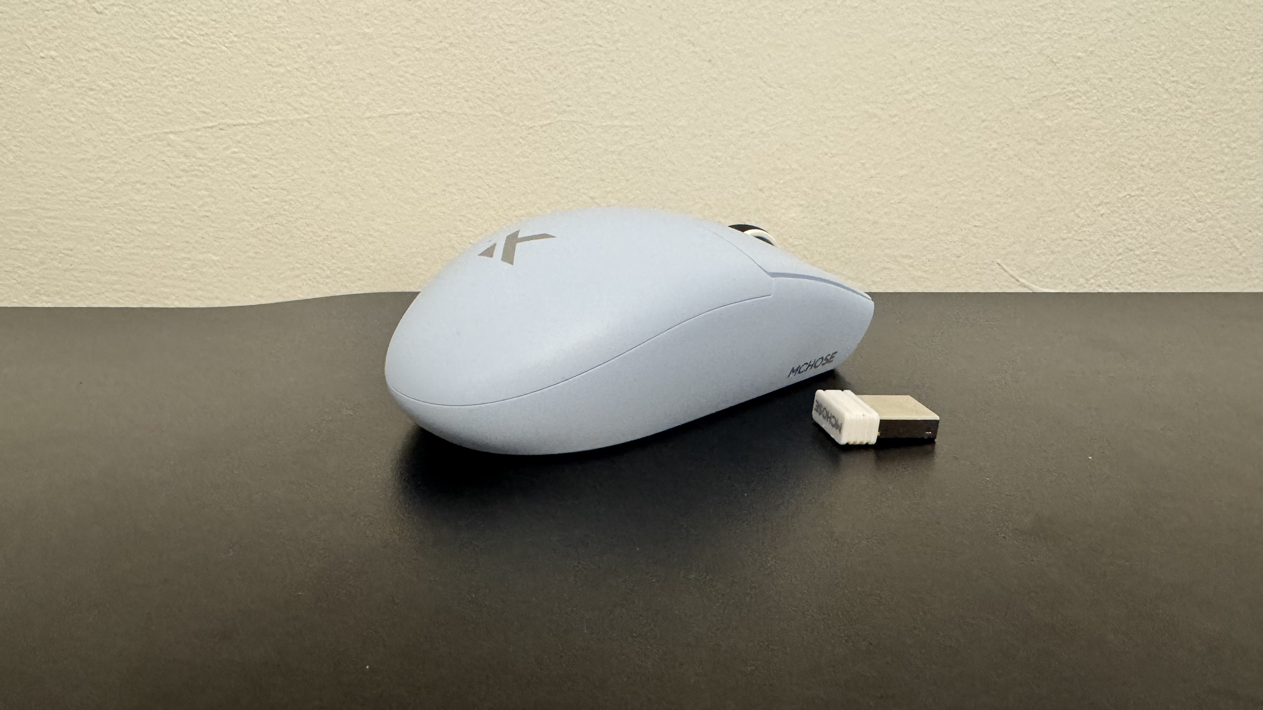 The blue Mchose G3 V2 gaming mouse from the right side with 2.4 GHz connector, on a black desk