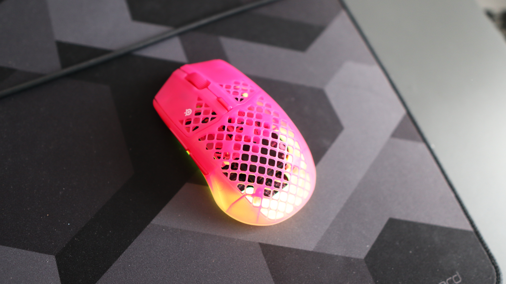 The SteelSeries Aerox 3 Wireless Gen 2 looking excellent in pink on a grey mousepad.
