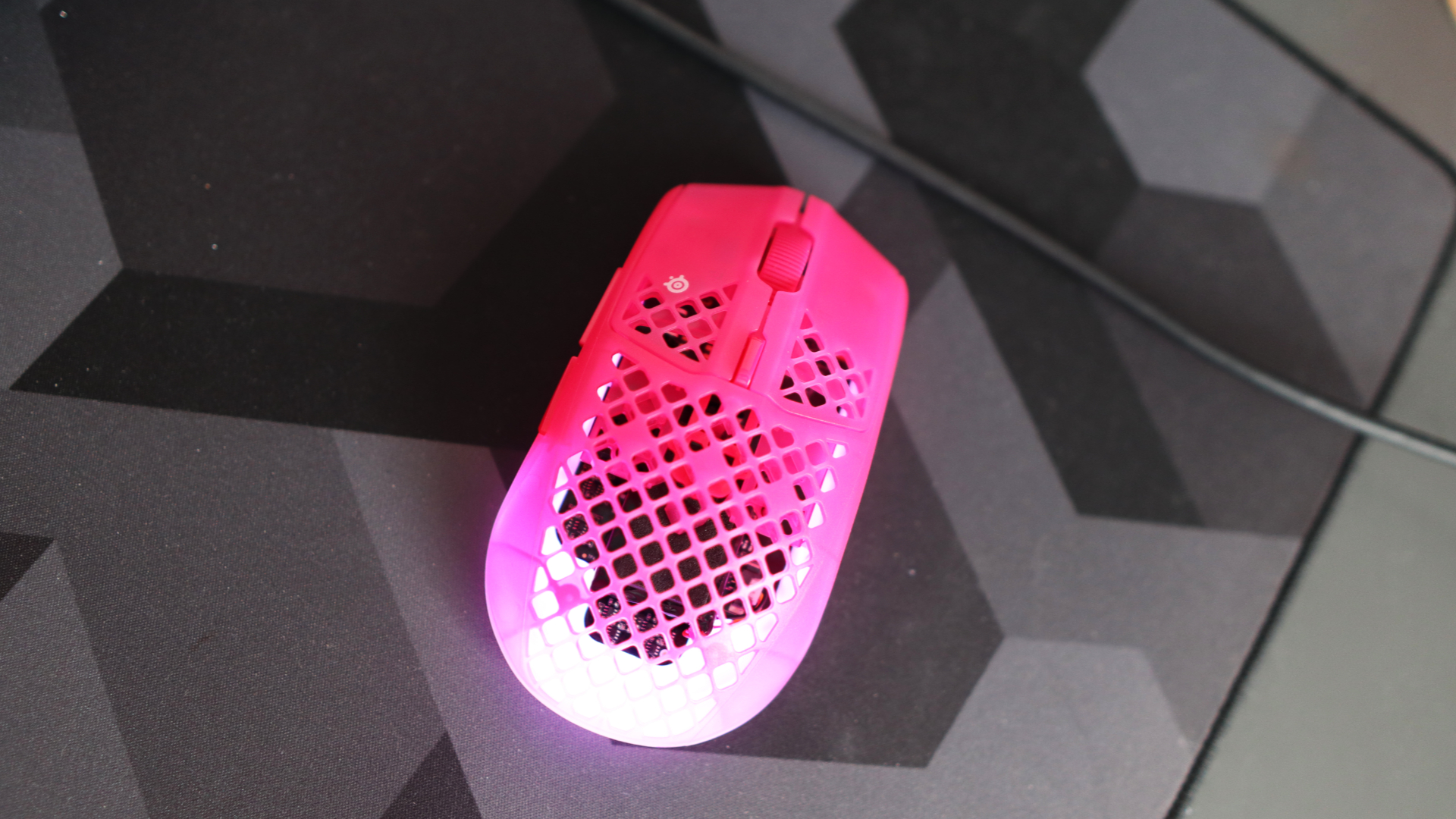The SteelSeries Aerox 3 Wireless Gen 2 looking excellent in pink on a grey mousepad.