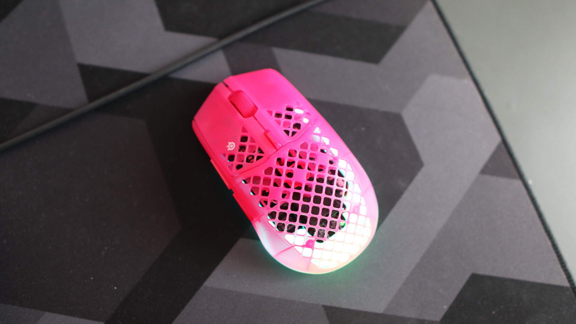 The SteelSeries Aerox 3 Wireless Gen 2 looking excellent in pink on a grey mousepad.
