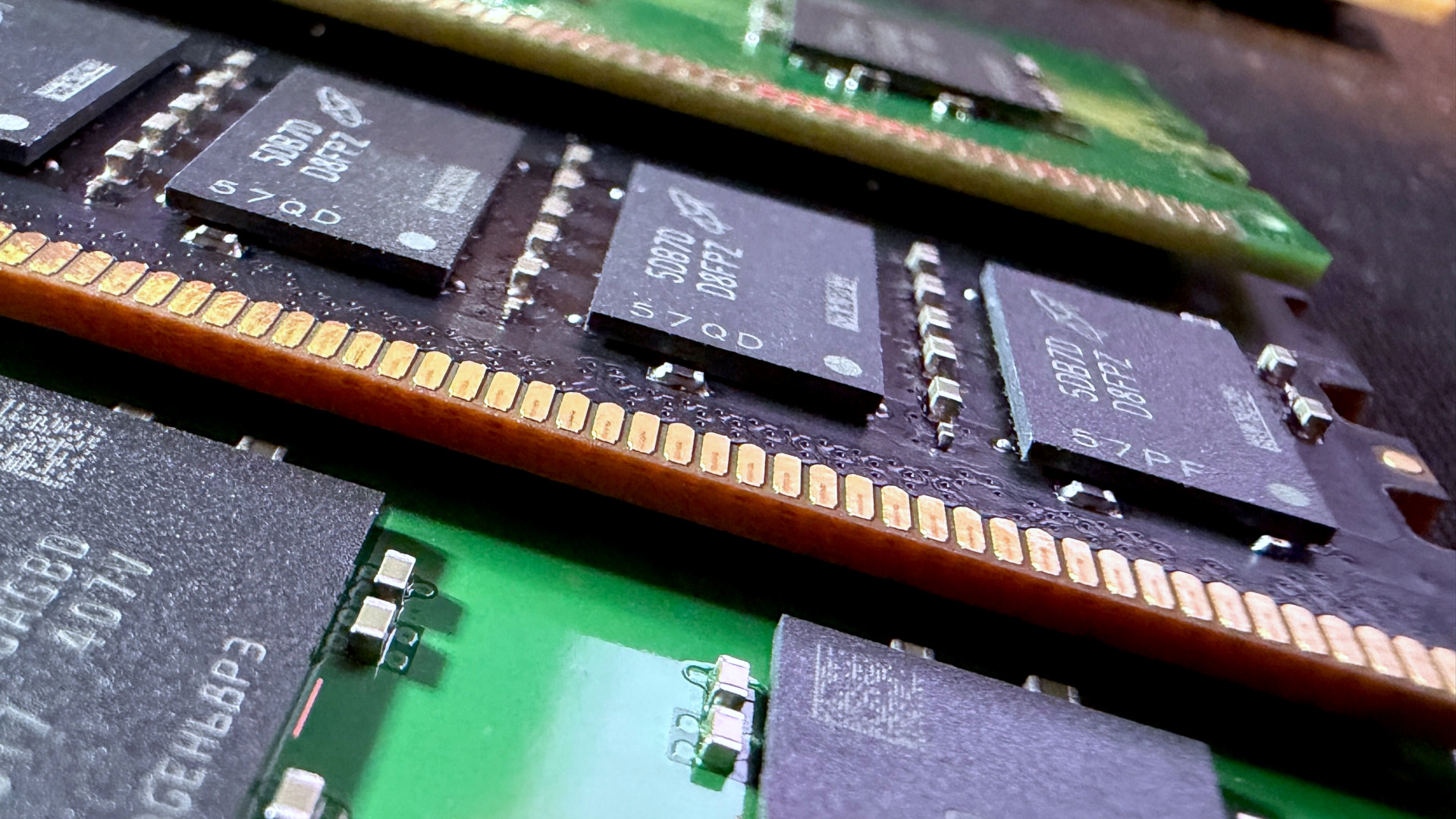 A close-up photo of multiple SK hynix and Micron DDR5 DIMMs, showing the memory modules installed on black/green PCBs