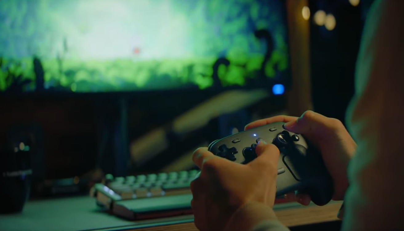A player hold a Steam Controller in front of a PC.