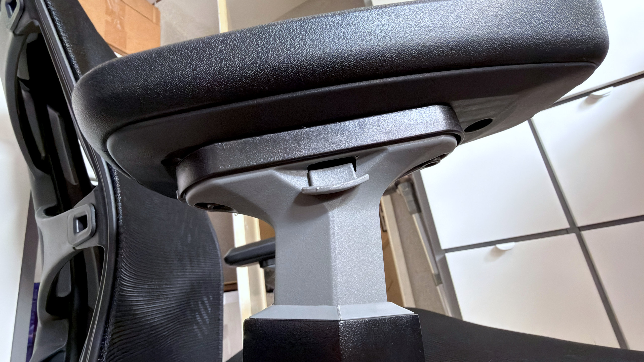 A photo of an Autonomous ErgoChair Ultra 2, showing a close-up view of an armrest and the latch used to adjust its height