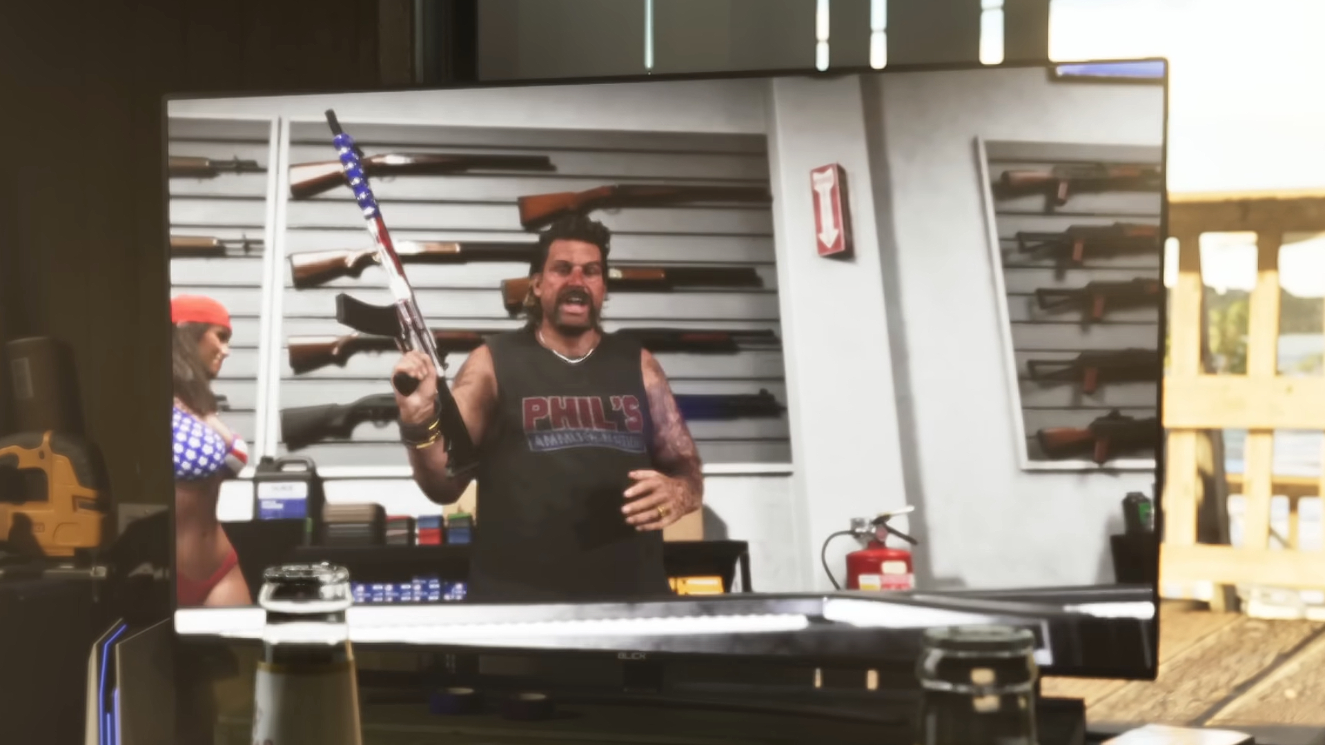 GTA 6 weapons: A gun store owner on TV with a rack of shotguns on the back wall.
