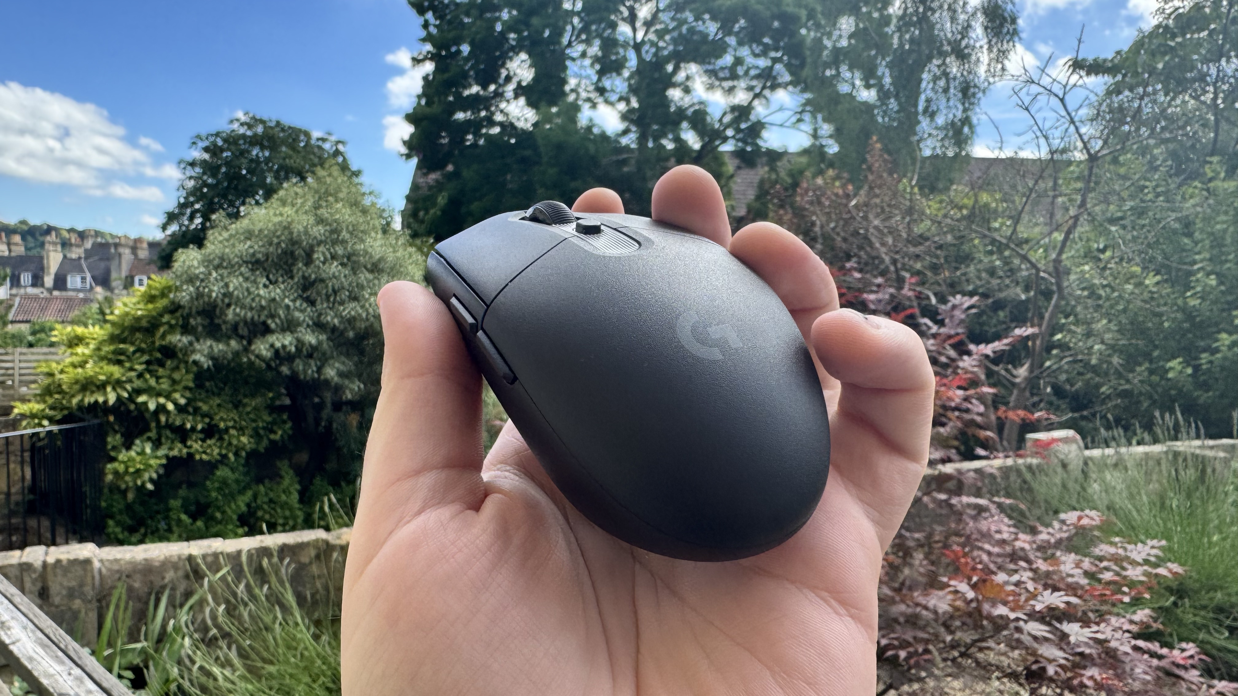 Logitech G305 X Superlight gaming mouse, held in a hand outside