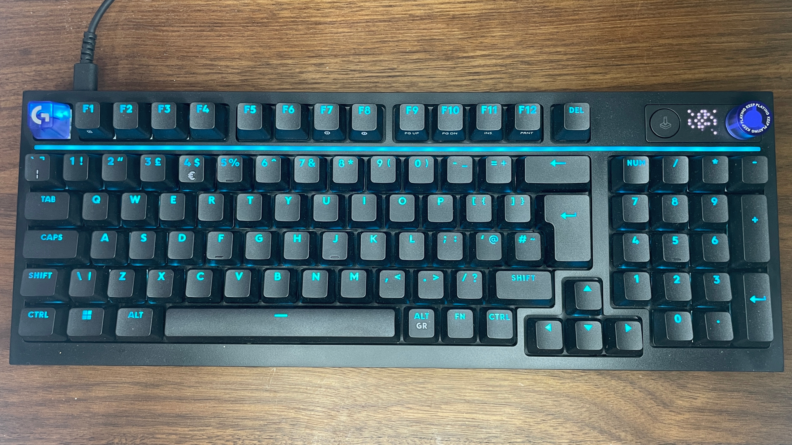 A Logitech G316 X gaming keyboard on a wooden desk.