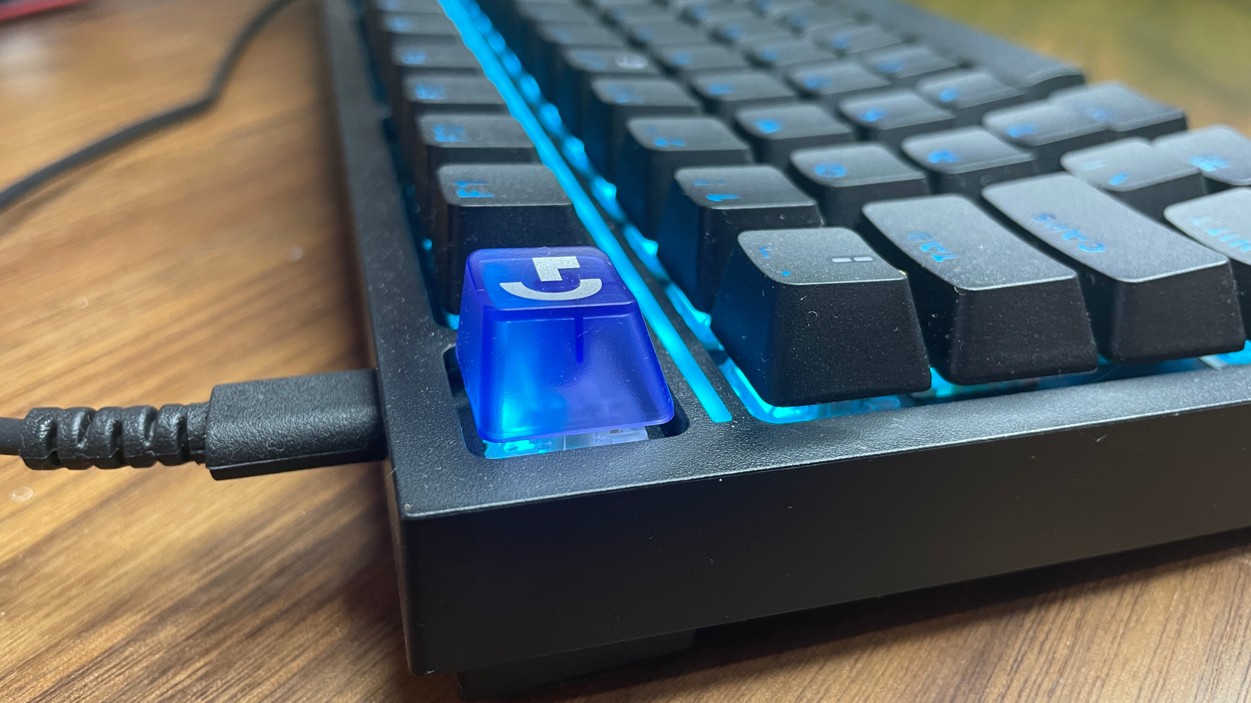 A Logitech G316 X gaming keyboard on a wooden desk.