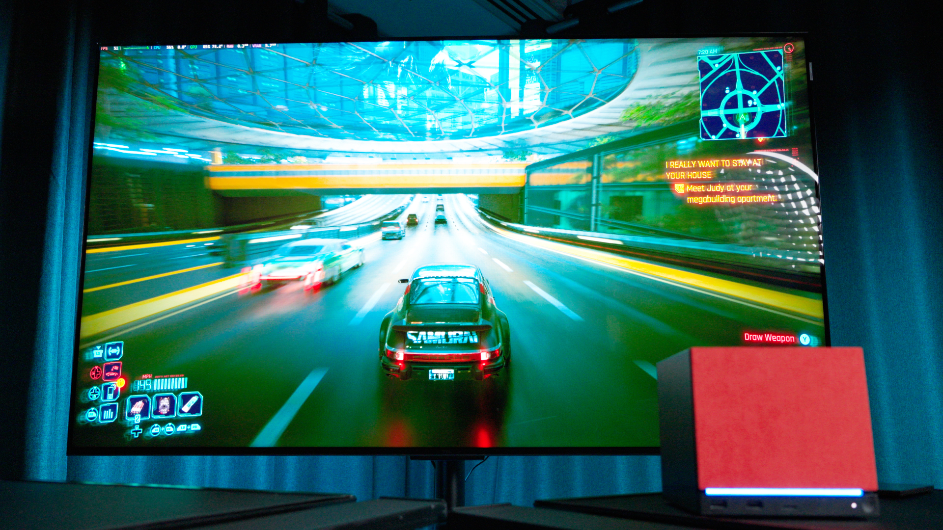 A Steam Machine with a red faceplate attached, in front of a TV