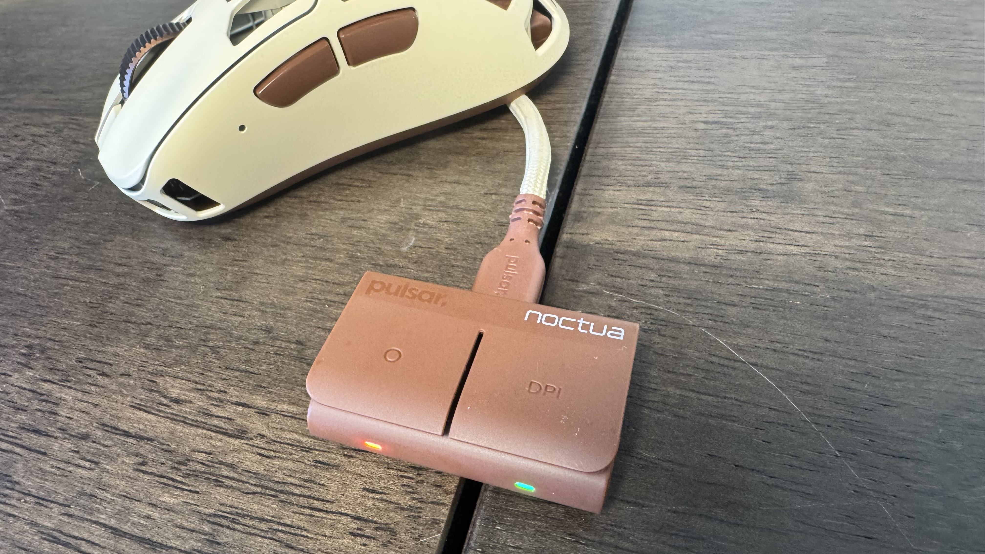 The Pulsar Feinmann F01 Noctua Edition gaming mouse and dongle on a wooden desk