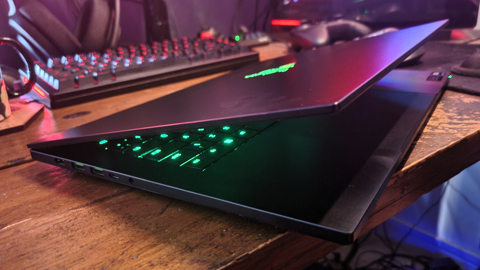 A Razer Blade 16 gaming laptop on a wooden desk, half closed