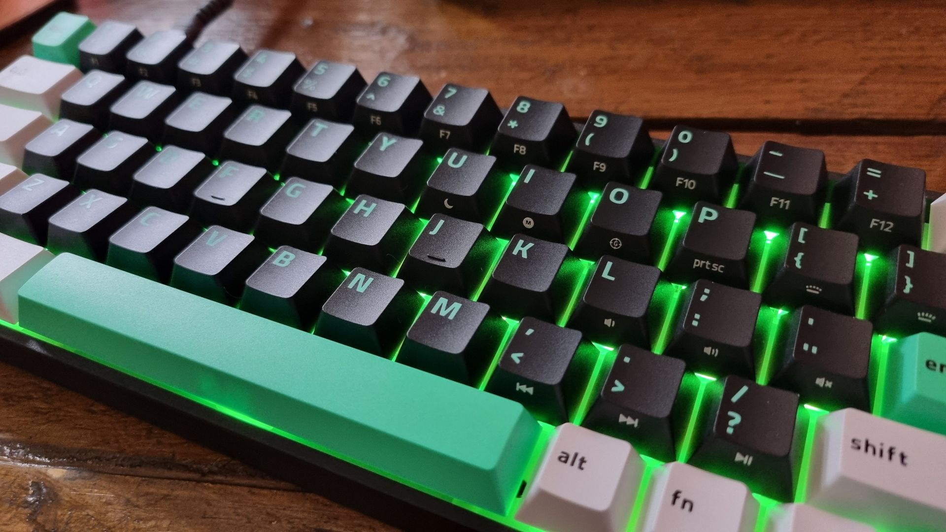 A close up of the keycaps of the Razer Reclusa X Mini 65% gaming keyboard, lit in green