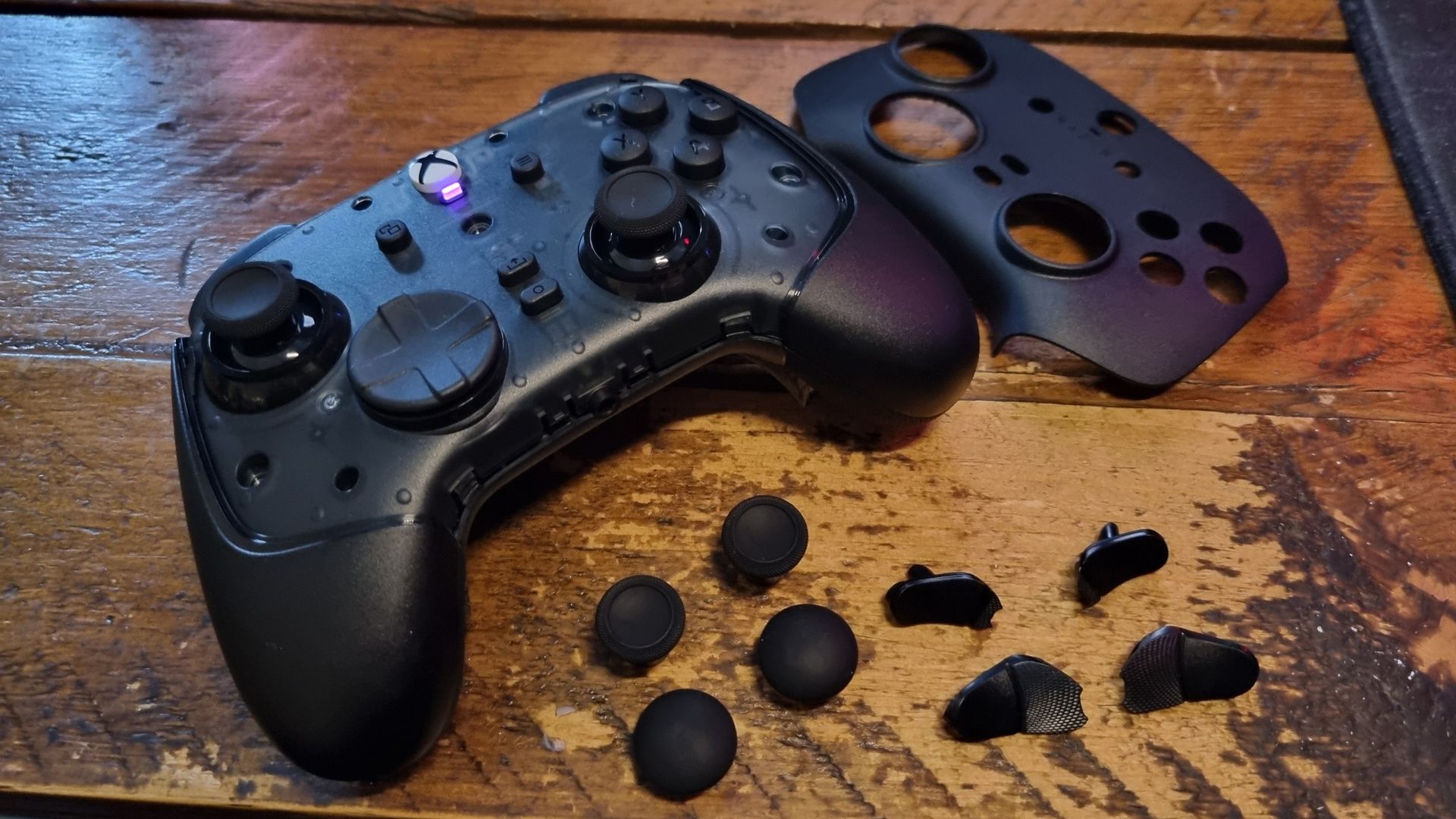 A Razer Wolverine V4 Pro, disassembled, with the magnetic faceplate removed and the extra thumbsticks and paddle button covers alongside