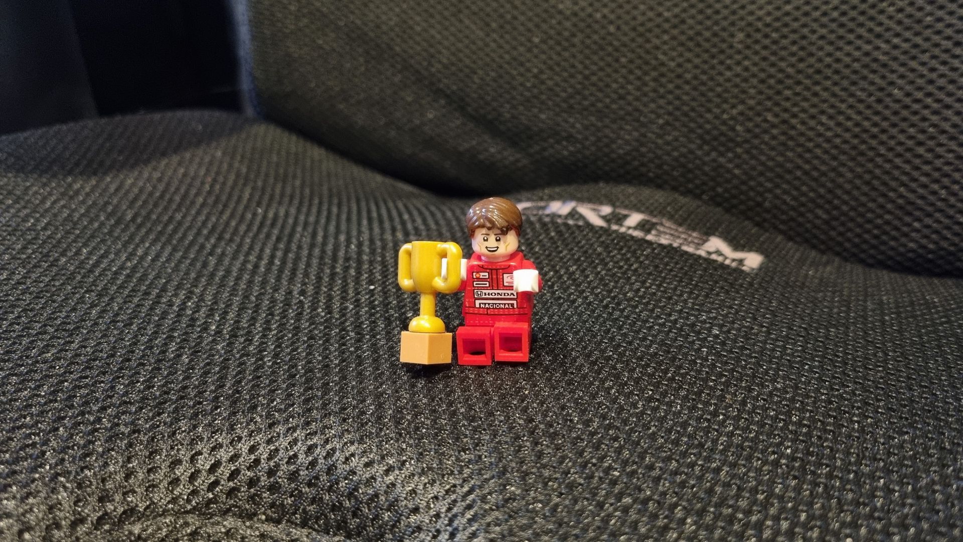 A Lego minifig of Ayrton Senna, perched atop a chair cushion